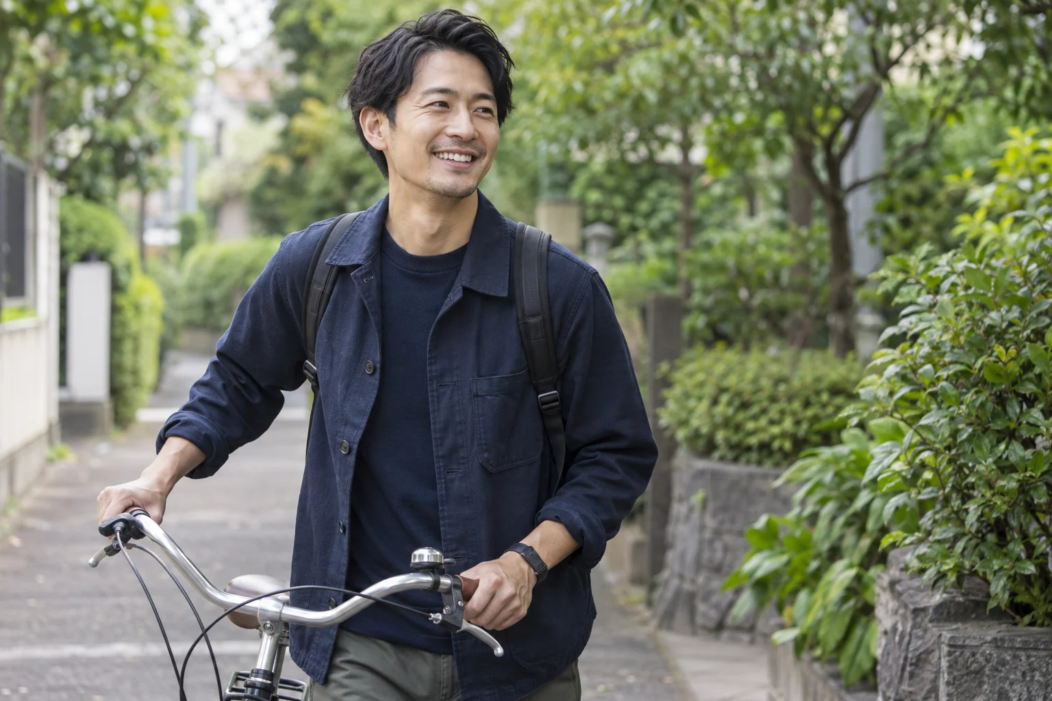 Man smiling while walking his bicycle along a leafy neighborhood path